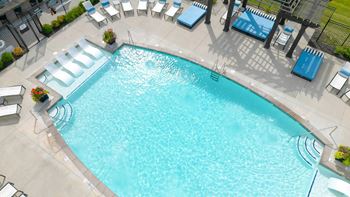 A large swimming pool with lounge chairs and tables around it